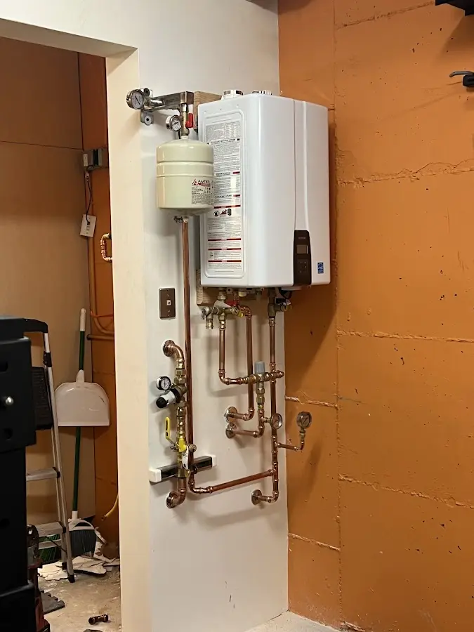Plumbing technician inspecting water heater connections in Kenmore